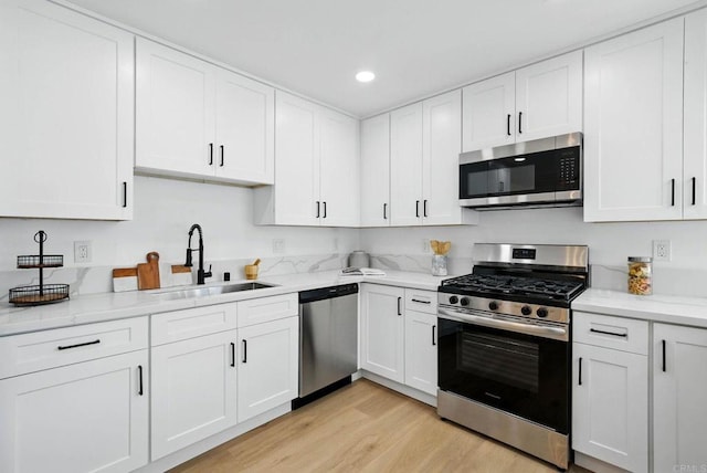 305 Spruce St, Chula Vista, CA 91911 - kitchen with stainless steel appliances, light wood-style floors, white cabinetry, recessed lighting, and light stone counters
