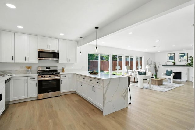 305 Spruce St, Chula Vista, CA 91911 - kitchen with appliances with stainless steel finishes, a peninsula, light wood finished floors, white cabinets, and light stone counters