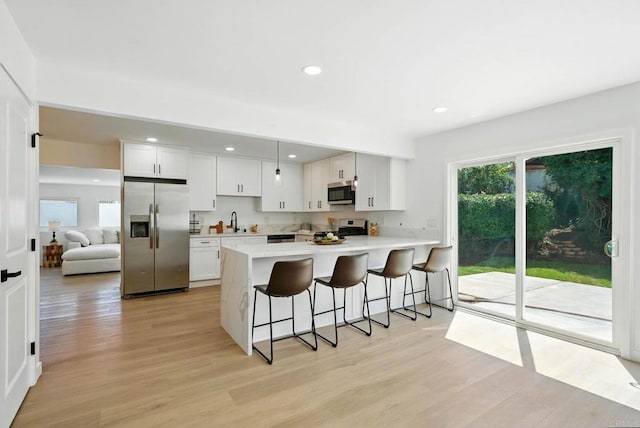 305 Spruce St, Chula Vista, CA 91911 - kitchen featuring appliances with stainless steel finishes, a peninsula, light countertops, a breakfast bar, and light wood finished floors