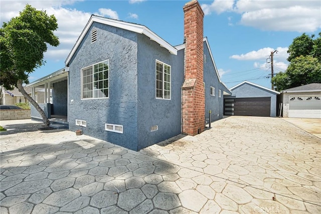 7803 Clive Ave, Whittier, CA 90606 - view of side of home with stucco siding, a detached garage, a chimney, and an outbuilding