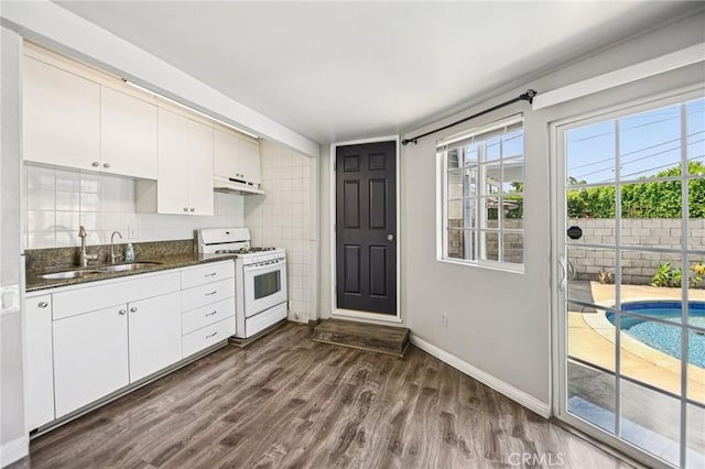 7803 Clive Ave, Whittier, CA 90606 - kitchen featuring white gas stove, dark wood-style floors, under cabinet range hood, dark stone countertops, and white cabinetry