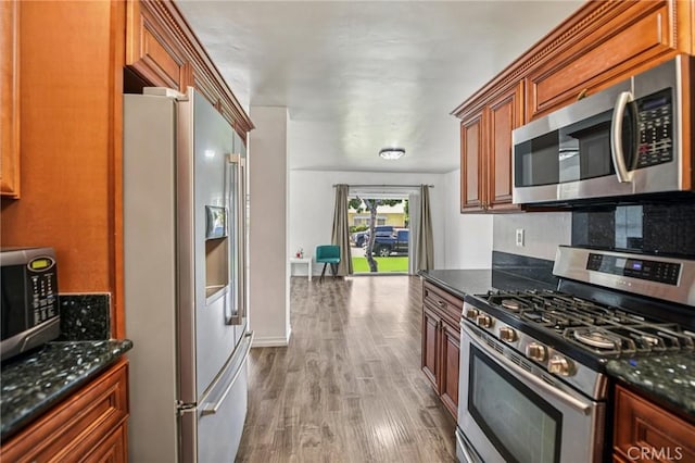 7803 Clive Ave, Whittier, CA 90606 - kitchen featuring stainless steel appliances, wood finished floors, dark stone counters, and brown cabinetry