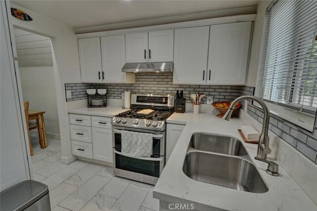 4519 Bresee Ave, Baldwin Park, CA 91706 - kitchen featuring range with two ovens, under cabinet range hood, light marble finish floors, and white cabinetry