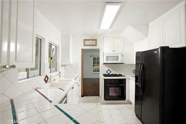 738 S Norton Ave, Los Angeles, CA 90005 - kitchen with black appliances, tile countertops, decorative backsplash, white cabinetry, and light tile patterned floors