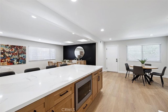 311 Prospect St, Oak View, CA 93022 - kitchen featuring stainless steel microwave, light wood-style floors, light stone counters, brown cabinetry, and recessed lighting