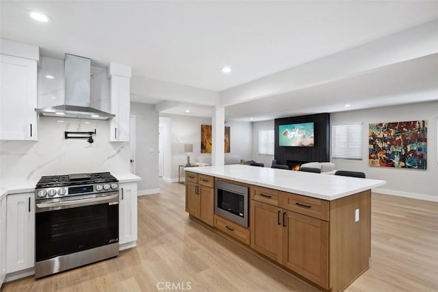311 Prospect St, Oak View, CA 93022 - kitchen with appliances with stainless steel finishes, wall chimney exhaust hood, open floor plan, white cabinetry, and light wood-style floors