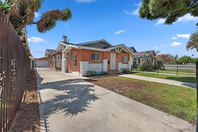 2018 W Martin Luther King Jr Blvd, Los Angeles, CA 90062 - view of front of house featuring concrete driveway, stucco siding, stone siding, a chimney, and a gate