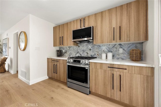 19331 Cindy Ln, Huntington Beach, CA 92646 - kitchen with stainless steel appliances, light wood-style floors, tasteful backsplash, modern cabinets, and light countertops