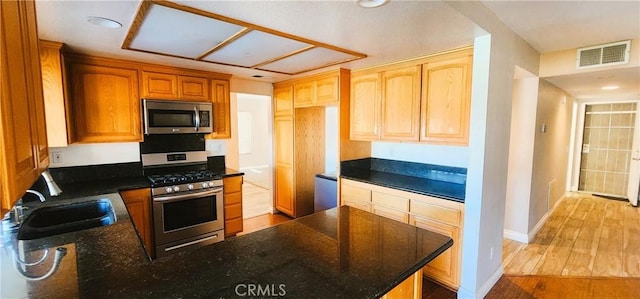 186 S Massachusetts St, Lake Elsinore, CA 92530 - kitchen featuring stainless steel appliances, a peninsula, dark stone counters, and light wood-style floors
