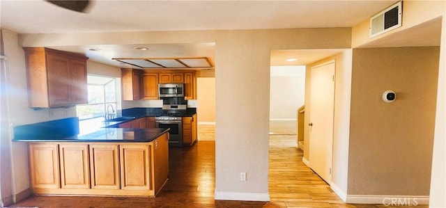 186 S Massachusetts St, Lake Elsinore, CA 92530 - kitchen featuring appliances with stainless steel finishes, wood finished floors, a peninsula, dark countertops, and brown cabinetry