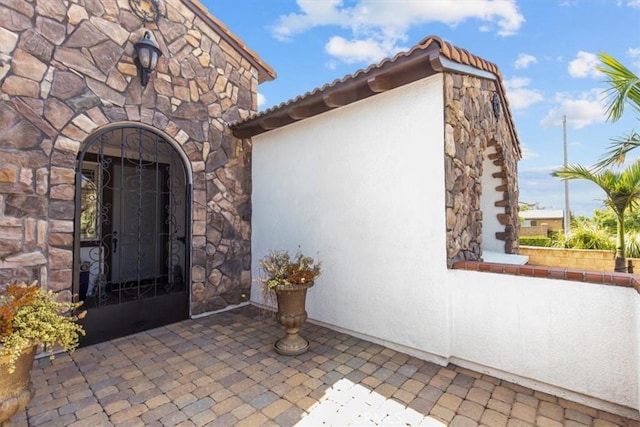 7145 Sunnyside Pl, Rancho Cucamonga, CA 91739 - view of exterior entry with stone siding, stucco siding, and a patio area