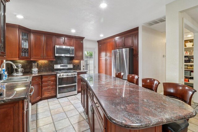 5070 Limerick Ave, Clairemont Mesa, CA 92117 - kitchen with appliances with stainless steel finishes, backsplash, recessed lighting, a center island, and glass insert cabinets
