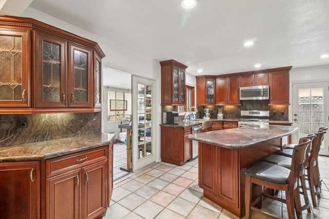 5070 Limerick Ave, Clairemont Mesa, CA 92117 - kitchen featuring appliances with stainless steel finishes, backsplash, recessed lighting, a breakfast bar area, and dark stone countertops