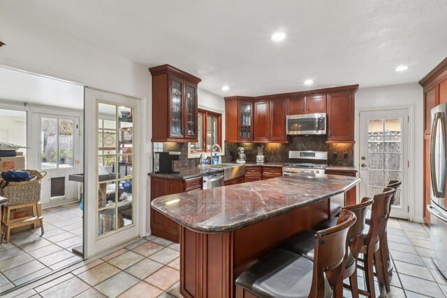5070 Limerick Ave, Clairemont Mesa, CA 92117 - kitchen with stainless steel appliances, backsplash, glass insert cabinets, a center island, and recessed lighting