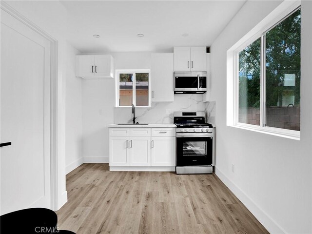 7055 Fallbrook Ave, West Hills, CA 91307 - kitchen featuring appliances with stainless steel finishes, light wood-style floors, white cabinets, and backsplash