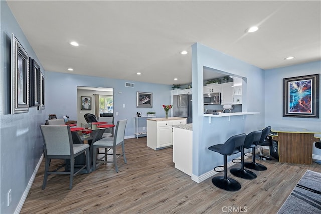 6963 Shamrock Ln, Rancho Cucamonga, CA 91701 - kitchen with stainless steel appliances, wood finished floors, light countertops, white cabinetry, and a peninsula
