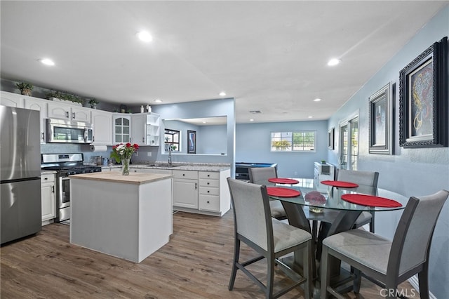 6963 Shamrock Ln, Rancho Cucamonga, CA 91701 - kitchen with appliances with stainless steel finishes, white cabinetry, recessed lighting, dark wood-style floors, and a kitchen island