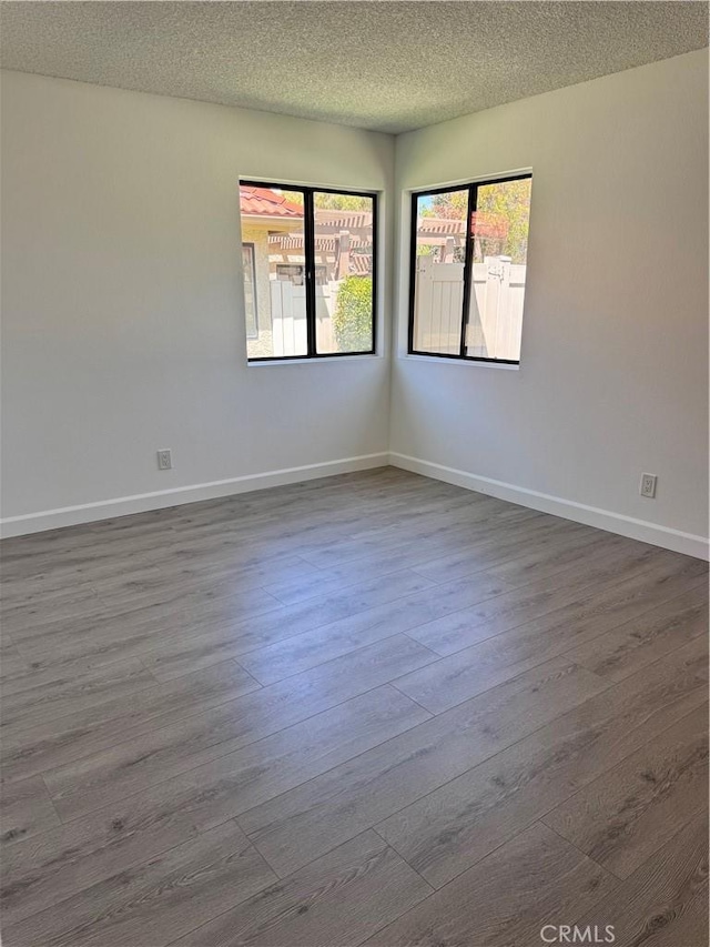 26226 Rainbow Glen Dr, Newhall, CA 91321 - spare room featuring healthy amount of natural light, dark wood-style flooring, and a textured ceiling
