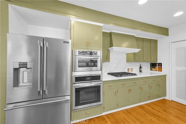 929 E Marshall Pl, Long Beach, CA 90807 - kitchen with appliances with stainless steel finishes, wall chimney exhaust hood, green cabinets, light countertops, and backsplash