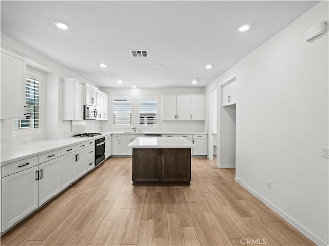 27148 Valley Oak Pl, Valencia, CA 91381 - kitchen featuring stainless steel microwave, oven, gas stovetop, white cabinets, and a kitchen island