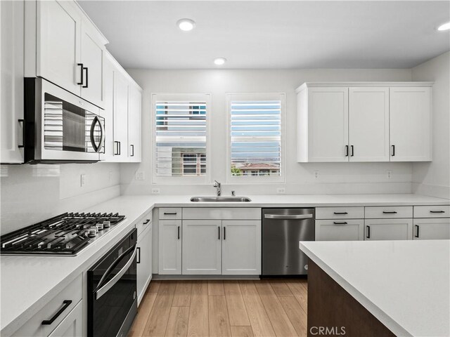 27148 Valley Oak Pl, Valencia, CA 91381 - kitchen with appliances with stainless steel finishes, white cabinets, light countertops, light wood-style floors, and recessed lighting