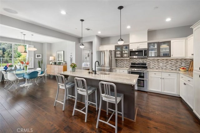 1012 Maggie Ln, Nipomo, CA 93444 - kitchen featuring stainless steel appliances, glass insert cabinets, tasteful backsplash, a breakfast bar area, and an island with sink