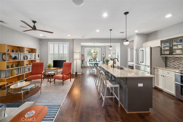 1012 Maggie Ln, Nipomo, CA 93444 - kitchen with light stone countertops, glass insert cabinets, white cabinetry, a ceiling fan, and an island with sink