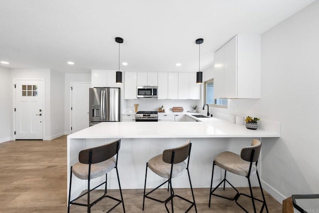 9121 Heatherdale St, Santee, CA 92071 - kitchen featuring stainless steel appliances, a peninsula, recessed lighting, a kitchen bar, and light countertops