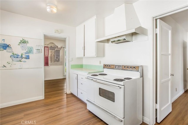 722 E 19th St, San Bernardino, CA 92404 - kitchen featuring electric range, premium range hood, white cabinetry, light wood-style floors, and light countertops