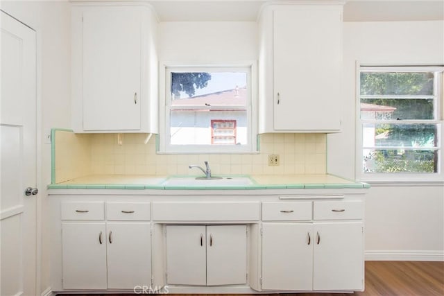722 E 19th St, San Bernardino, CA 92404 - kitchen with white cabinetry, tile countertops, decorative backsplash, and wood finished floors