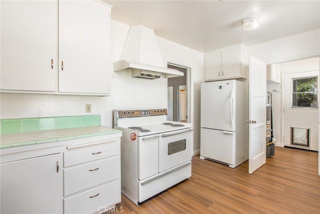 722 E 19th St, San Bernardino, CA 92404 - kitchen with white appliances, custom exhaust hood, white cabinetry, light wood finished floors, and tile countertops