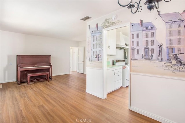 722 E 19th St, San Bernardino, CA 92404 - interior space featuring white stove, ventilation hood, a chandelier, light wood-type flooring, and white cabinetry