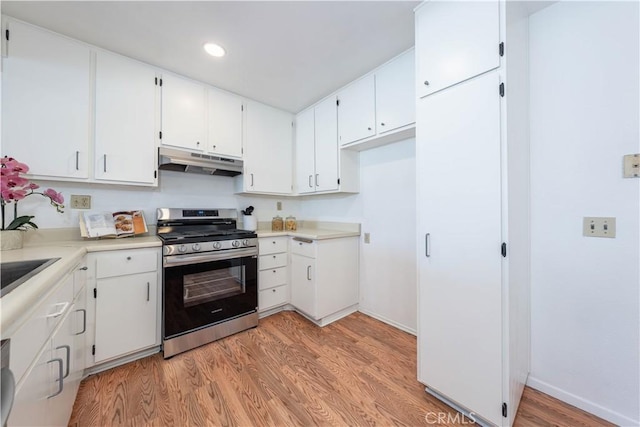 13801 Shirley St Unit 14, Garden Grove, CA 92843 - kitchen with stainless steel gas range oven, under cabinet range hood, light wood-style floors, white cabinets, and light countertops