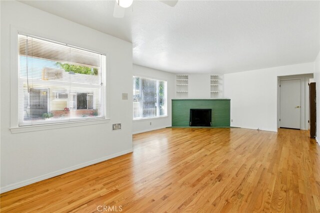 2723 57th St, Sacramento, CA 95817 - unfurnished living room featuring light wood-type flooring, built in features, a ceiling fan, and a fireplace