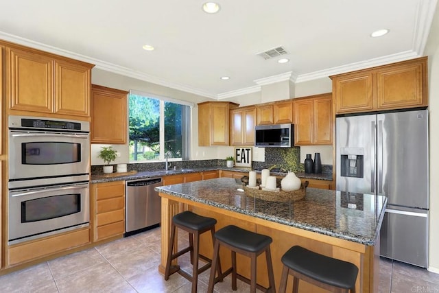 43883 Brookhaven Ct, Temecula, CA 92592 - kitchen with appliances with stainless steel finishes, light tile patterned floors, brown cabinets, a center island, and a breakfast bar area