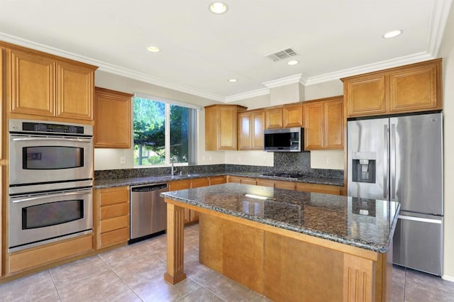 43883 Brookhaven Ct, Temecula, CA 92592 - kitchen with appliances with stainless steel finishes, a center island, ornamental molding, dark stone counters, and light tile patterned floors