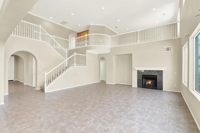 43883 Brookhaven Ct, Temecula, CA 92592 - unfurnished living room with a high ceiling, a warm lit fireplace, tile patterned floors, crown molding, and arched walkways