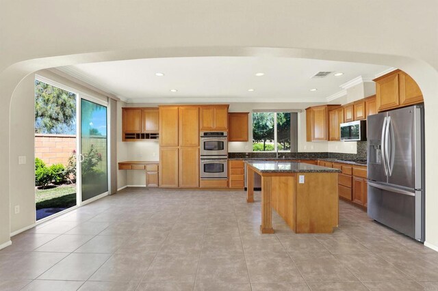 43883 Brookhaven Ct, Temecula, CA 92592 - kitchen featuring appliances with stainless steel finishes, ornamental molding, a kitchen island, brown cabinetry, and recessed lighting