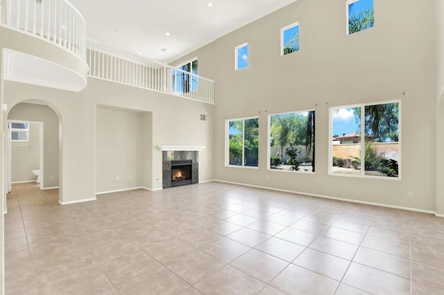 43883 Brookhaven Ct, Temecula, CA 92592 - unfurnished living room featuring tile patterned floors, a high ceiling, arched walkways, and a high end fireplace