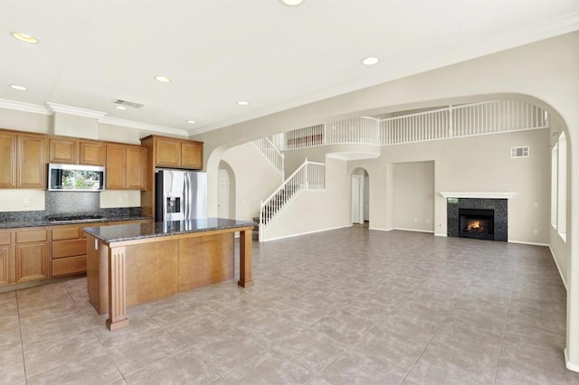 43883 Brookhaven Ct, Temecula, CA 92592 - kitchen featuring stainless steel appliances, arched walkways, a center island, ornamental molding, and brown cabinets