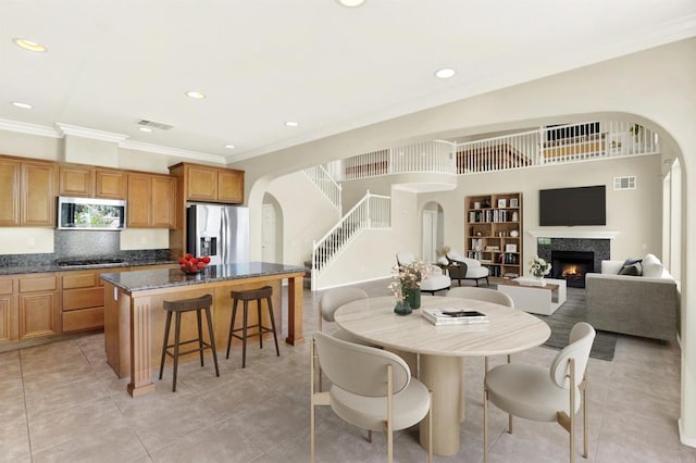 43883 Brookhaven Ct, Temecula, CA 92592 - dining area featuring arched walkways, ornamental molding, recessed lighting, a lit fireplace, and built in features