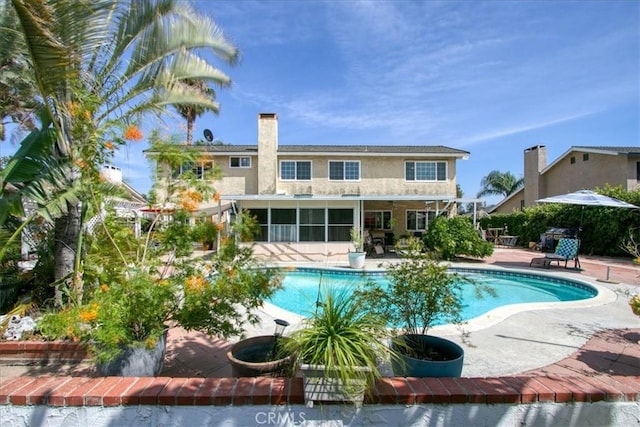 2374 Corydon Ave, Norco, CA 92860 - back of property featuring a patio area, an outdoor pool, a sunroom, stucco siding, and a chimney