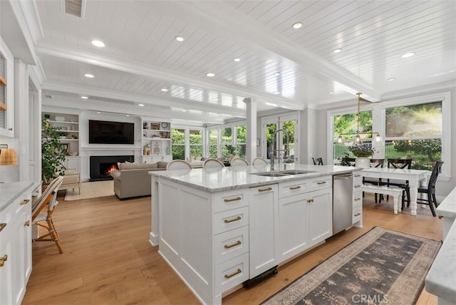 19256 Jasper Hill Rd, Lake Forest, CA 92679 - kitchen featuring a lit fireplace, white cabinetry, a kitchen island with sink, light wood-style flooring, and light stone counters