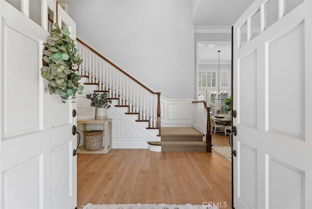 19256 Jasper Hill Rd, Lake Forest, CA 92679 - entrance foyer featuring stairs, light wood finished floors, crown molding, a decorative wall, and wainscoting