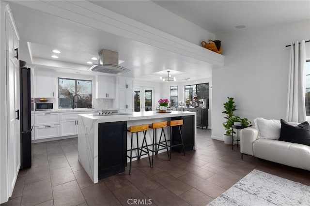 5027 Sleeping Indian Rd, Fallbrook, CA 92028 - kitchen with island range hood, open floor plan, light countertops, a large island, and white cabinetry