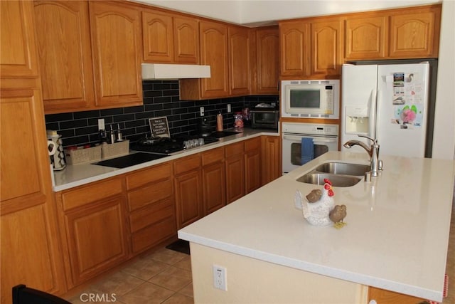 31256 Firestone St, Temecula, CA 92591 - kitchen with white appliances, under cabinet range hood, light countertops, an island with sink, and backsplash