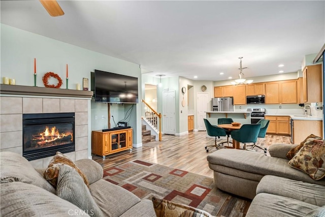 40209 Chelsea Ct, Palmdale, CA 93551 - living room with light wood-style flooring, a tile fireplace, stairs, and recessed lighting