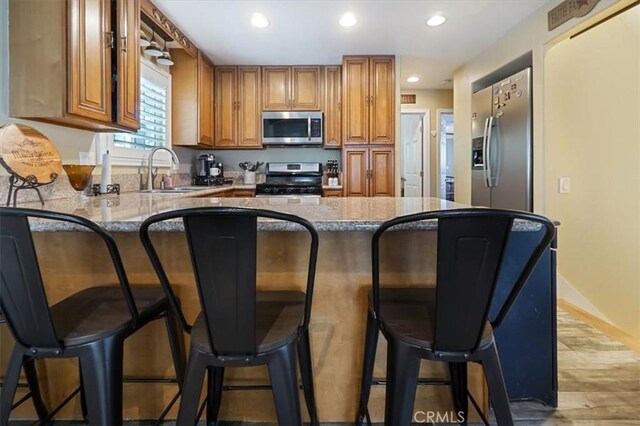 182 Darfo Dr, Crestline, CA 92325 - kitchen featuring stainless steel appliances, brown cabinetry, a peninsula, recessed lighting, and a kitchen breakfast bar