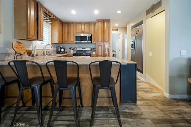 182 Darfo Dr, Crestline, CA 92325 - kitchen with appliances with stainless steel finishes, a peninsula, brown cabinets, recessed lighting, and a kitchen bar