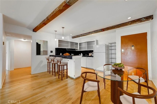 1701 Clinton St Unit 402, Los Angeles, CA 90026 - kitchen with white appliances, beamed ceiling, a peninsula, light wood-style flooring, and a breakfast bar area